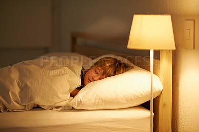 Buy stock photo Boy, bed and rest for night, sleeping and tired with fatigue and peace. Child, dreaming and exhausted with pyjamas, blanket and bedroom with lamp for serene childhood at home or house for calm kid