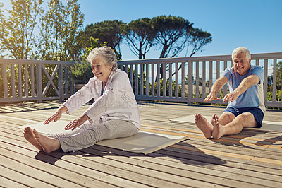 Buy stock photo Shot of a senior couple doing yoga together on their patio outside