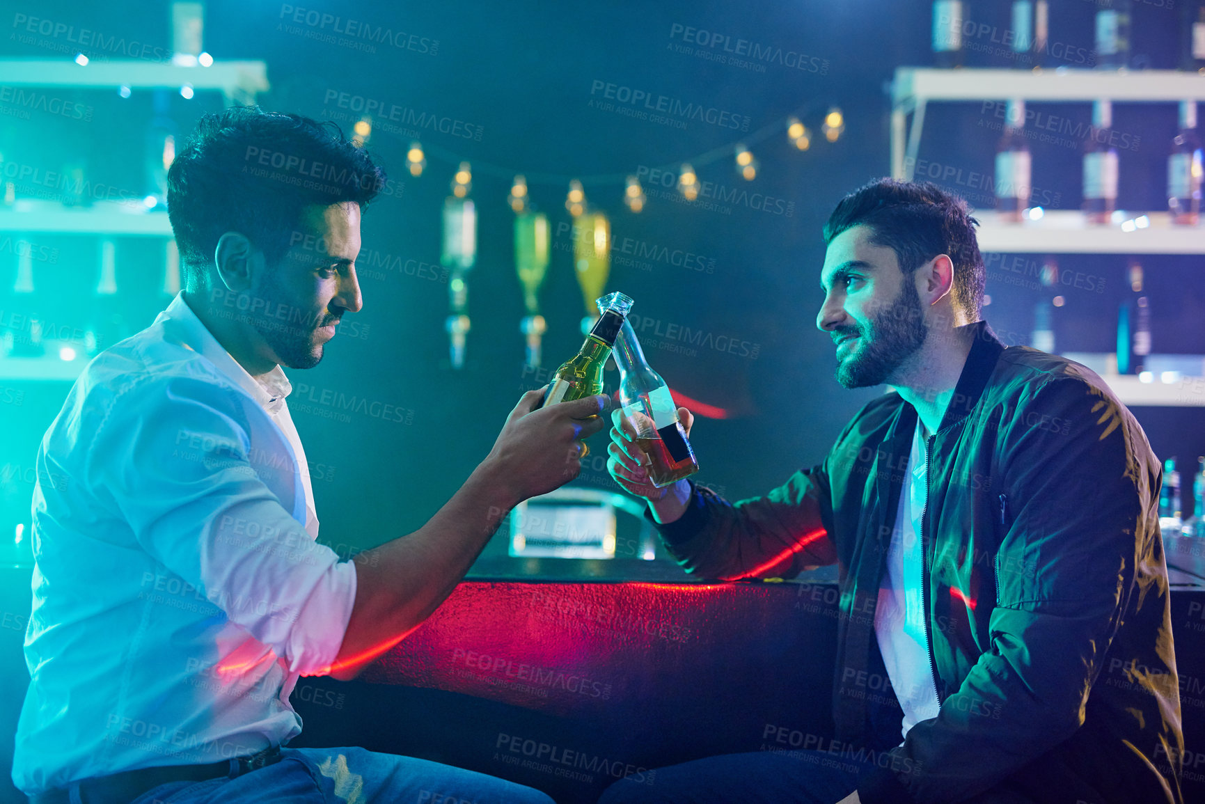 Buy stock photo Men, pub and toast with beer bottle in club, bar and rave for party or cheers. People, friends and salute with alcohol for downtime from work at event, festival and nightclub in the city at night