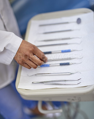 Buy stock photo Closeup shot of an unrecognisable dentist working with a tray of surgical instruments
