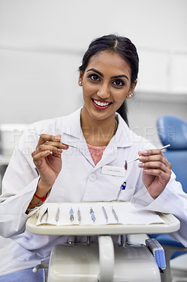 Buy stock photo Portrait of a young female dentist working with surgical instruments in her office