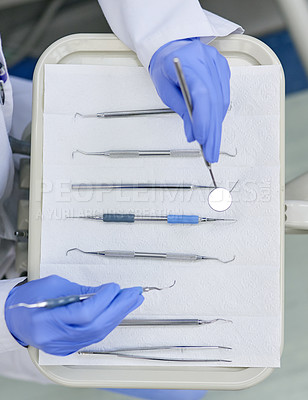 Buy stock photo High angle shot of an unrecognisable dentist working with a tray of surgical instruments