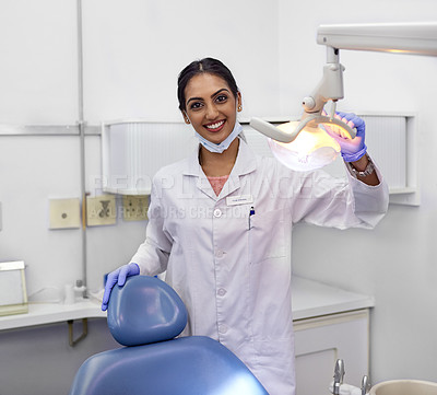 Buy stock photo Portrait of a young female dentist standing alongside the dental chair in her office