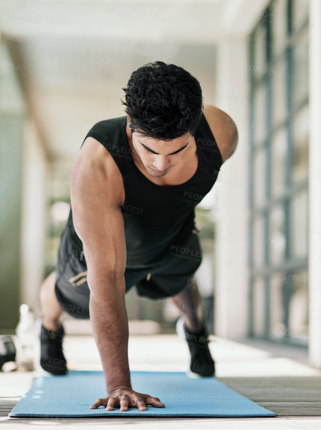 Buy stock photo Shot of a young man doing pushups during his workout at home