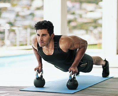Buy stock photo Shot of a young man doing pushups with dumbbells at home