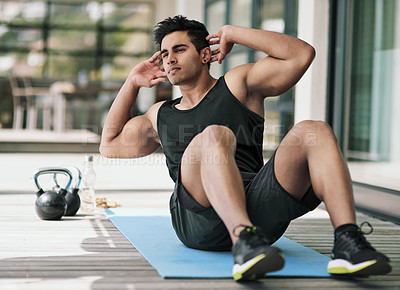 Buy stock photo Shot of a young man doing crunches during his workout at home