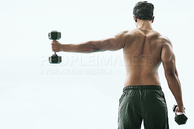 Buy stock photo Rearview shot of a shirtless young man working out with dumbbells outside