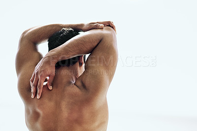 Buy stock photo Rearview shot of a shirtless young man stretching his arms outside