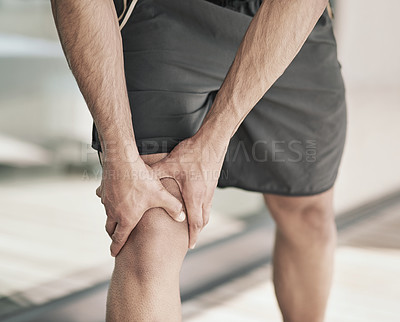 Buy stock photo Shot of an unidentifiable sportsman holding his injured knee while standing outside