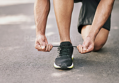 Buy stock photo Shot of an unidentifiable young sportsman tying his shoelaces before a run