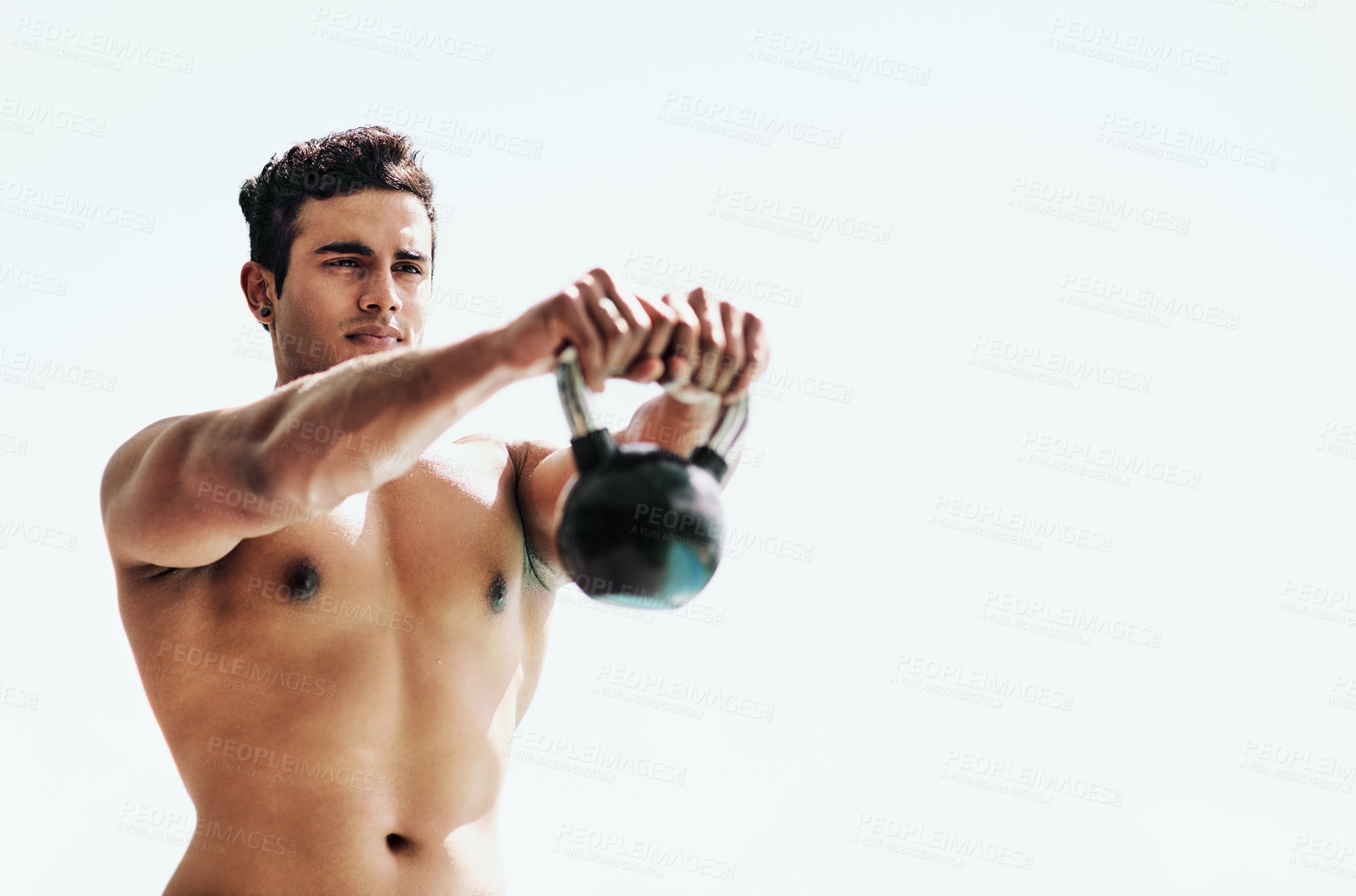 Buy stock photo Shot of a shirtless young man posing with a kettle bell outside