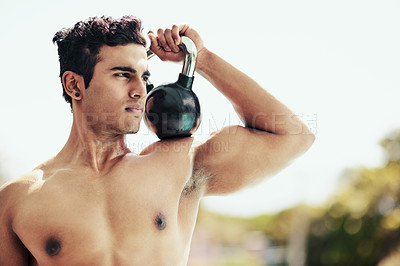 Buy stock photo Shot of a shirtless young man posing with a kettle bell outside