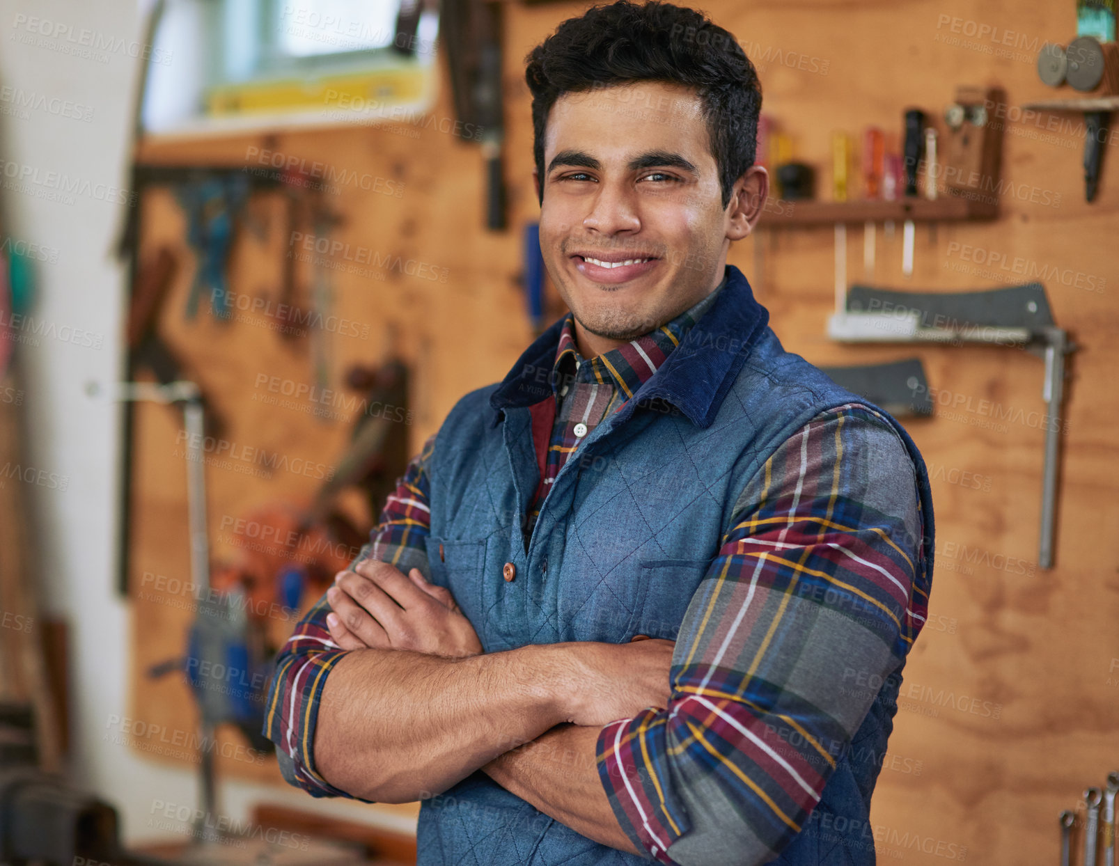 Buy stock photo Portrait of a happy handyman standing in his workshop with his arms folded