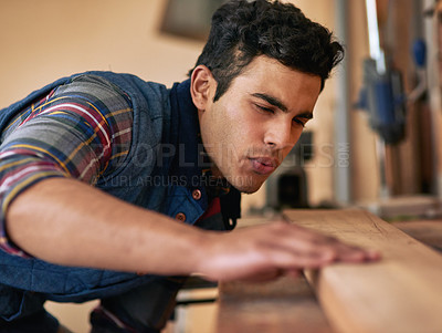 Buy stock photo Shot of a focused handyman examining a piece of wood while working in his workshop