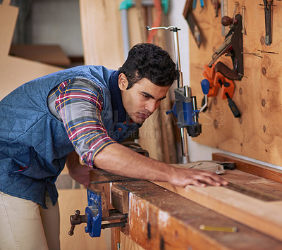 Buy stock photo Shot of a focused handyman measuring a piece of wood while working in his workshop