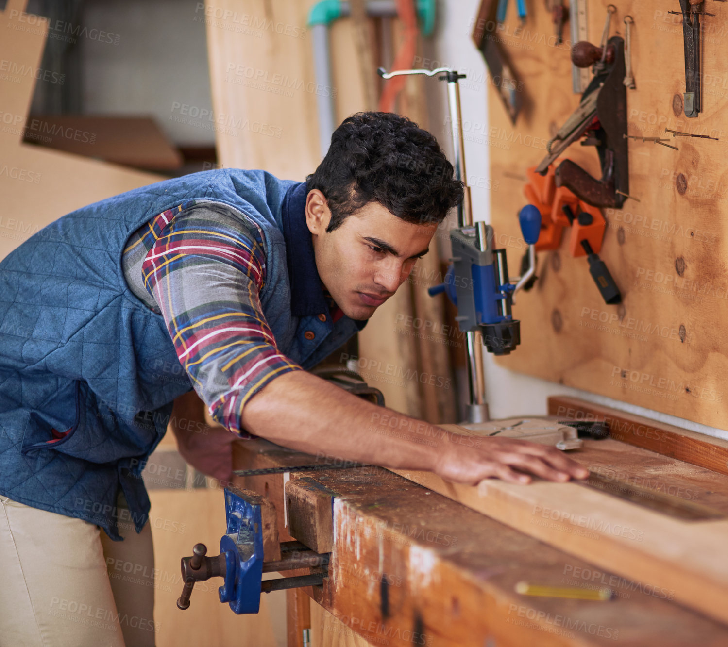 Buy stock photo Shot of a focused handyman measuring a piece of wood while working in his workshop