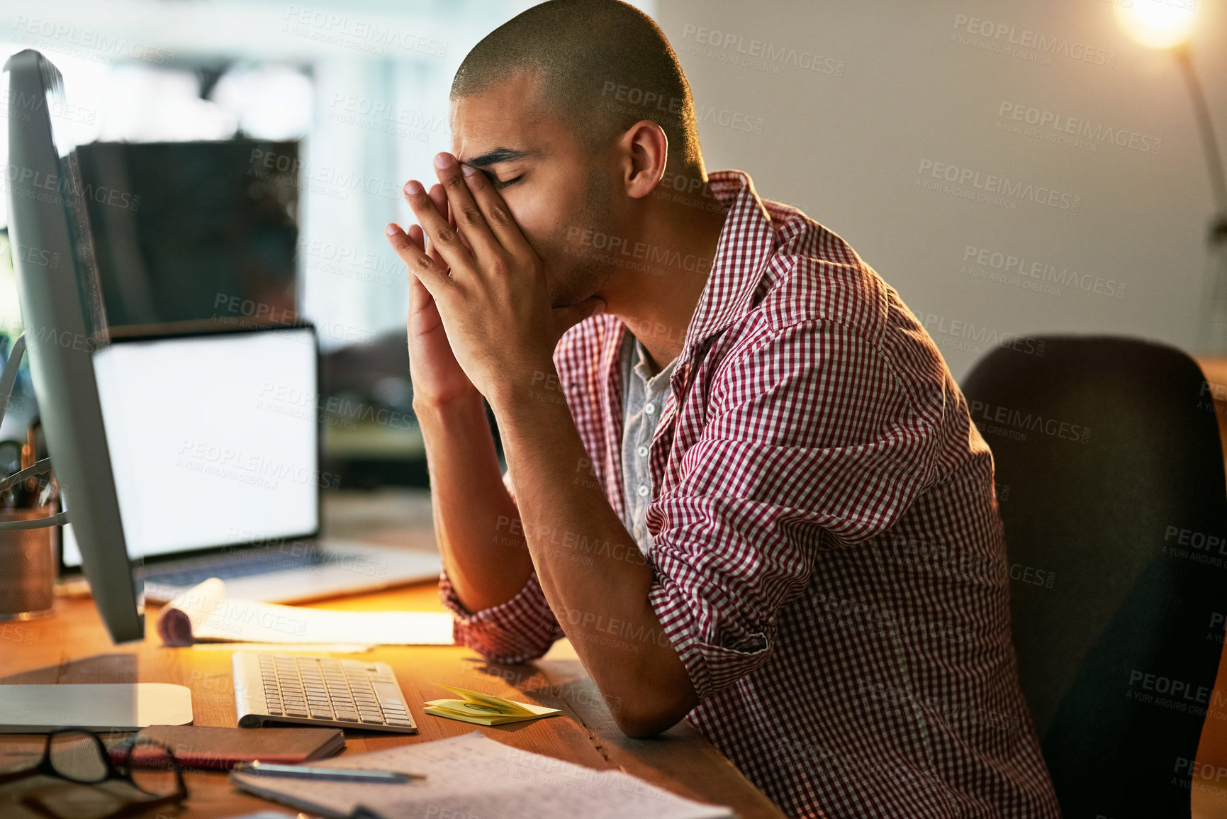 Buy stock photo Cropped shot of a young designer looking stressed out while working late in an office