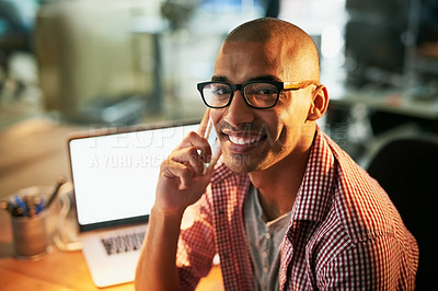 Buy stock photo Portrait of a young designer talking on a cellphone while working late in an office