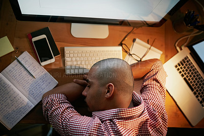 Buy stock photo High angle shot of a young designer sleeping on his desk while working late in an office
