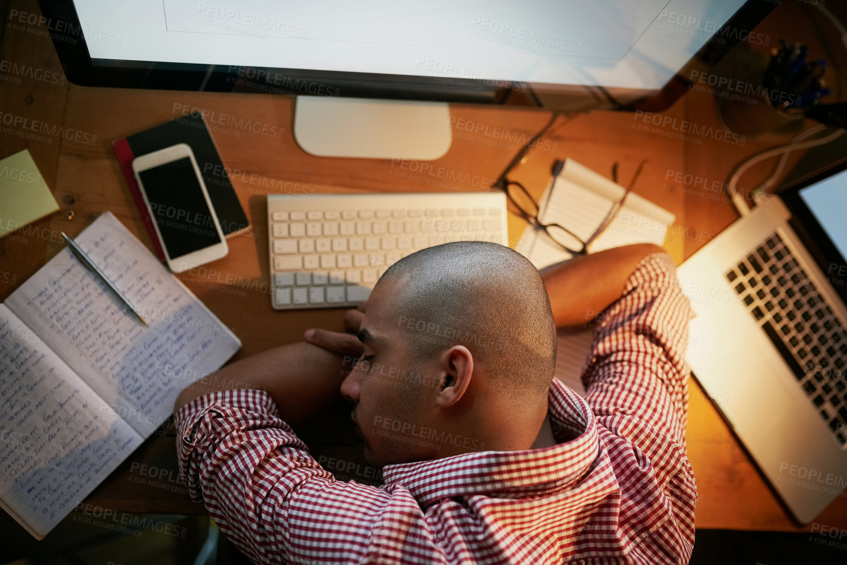 Buy stock photo High angle shot of a young designer sleeping on his desk while working late in an office