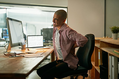 Buy stock photo Cropped shot of a young designer experiencing back pain while working late at his desk