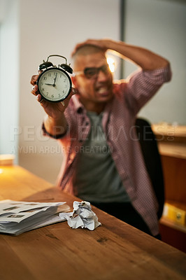 Buy stock photo Portrait of a young designer holding an alarm clock and looking stressed out while working late in an office