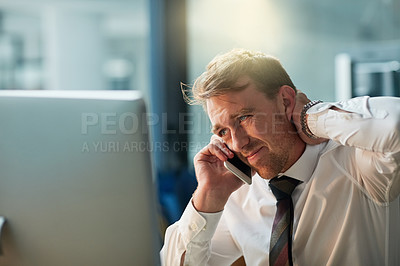 Buy stock photo Shot of a tired businessman answering his cellphone while sitting at his desk
