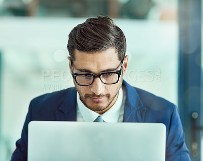 Buy stock photo Shot of a focused executive in glasses working on a laptop in an office
