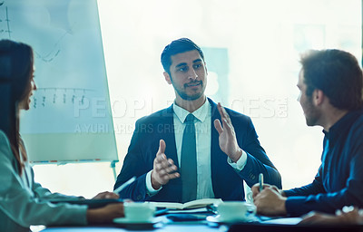 Buy stock photo Shot of a young executive talking during a meeting with colleagues in a boardoom