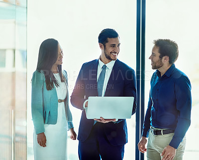 Buy stock photo Shot of three businesspeople working together on a laptop while standing in an office