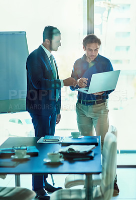 Buy stock photo Shot of a two businessman working together on a laptop while standing in an office