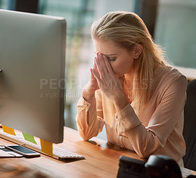 Buy stock photo Shot of an exhausted young businesswoman working on a computer in an office