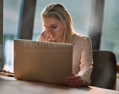 Buy stock photo Shot of an exhausted young businesswoman working on a laptop in an office