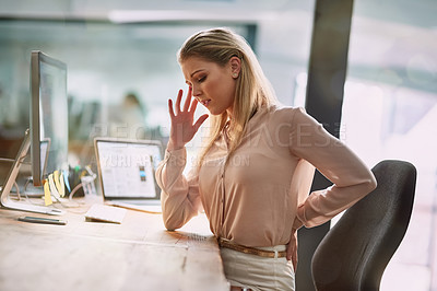Buy stock photo Shot of a young businesswomen suffering from back pain while sitting at her desk in an office