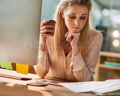 Buy stock photo Shot of a young businesswoman sitting at her desk in an office reading paperwork