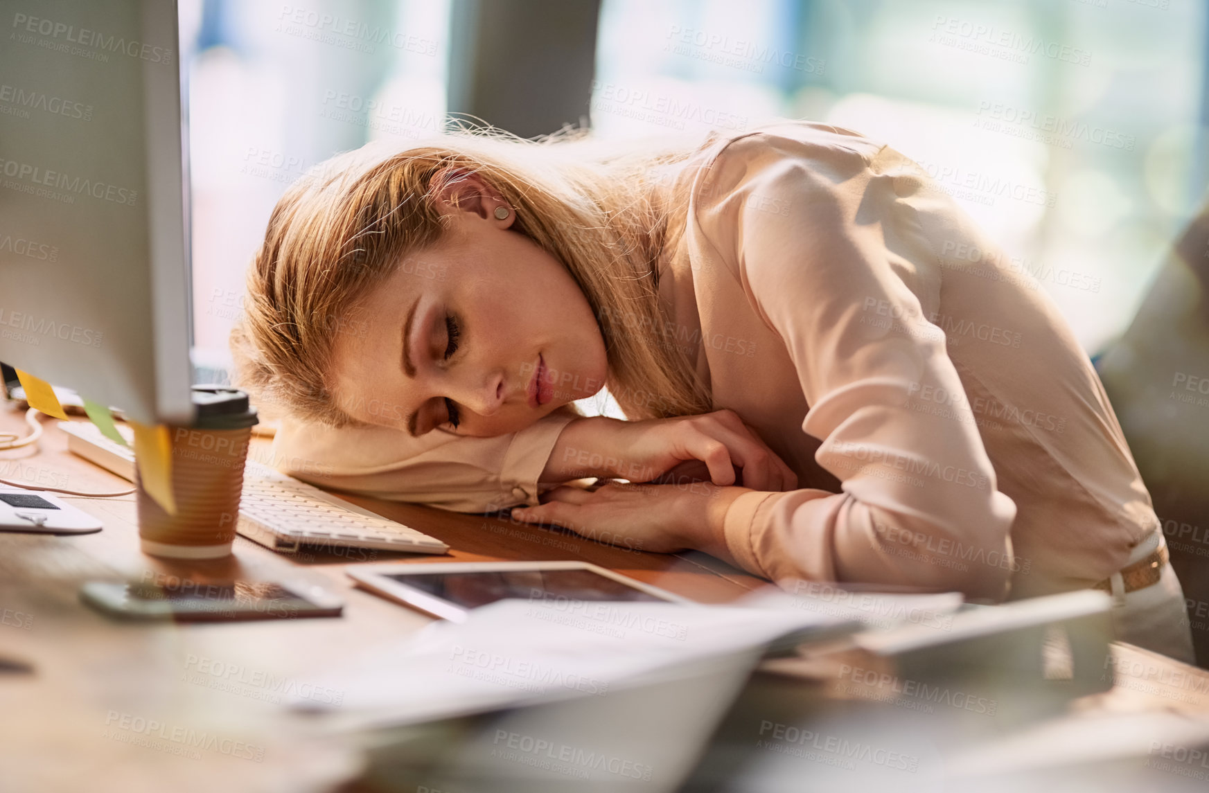 Buy stock photo Shot of an exhausted young businesswoman asleep at her desk in an office