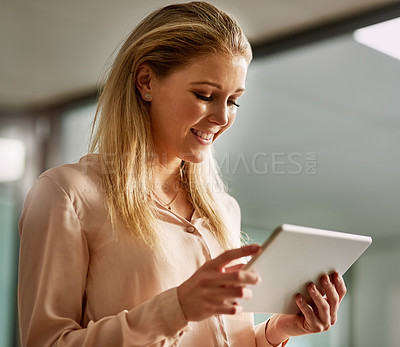 Buy stock photo Shot of a smiling young businesswoman working on a digital tablet in an office