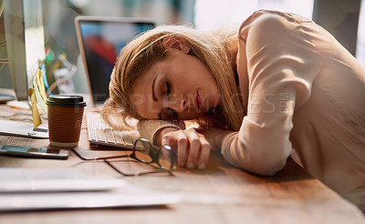 Buy stock photo Shot of an exhausted young businesswoman asleep at her desk in an office