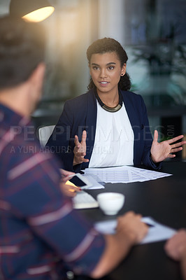Buy stock photo Shot of a young professional leading her team through an idea while sitting at a table in an office