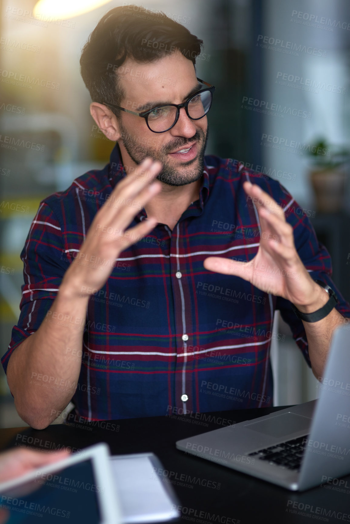 Buy stock photo Shot of a young professional leading his team through an idea while sitting at a table in an office