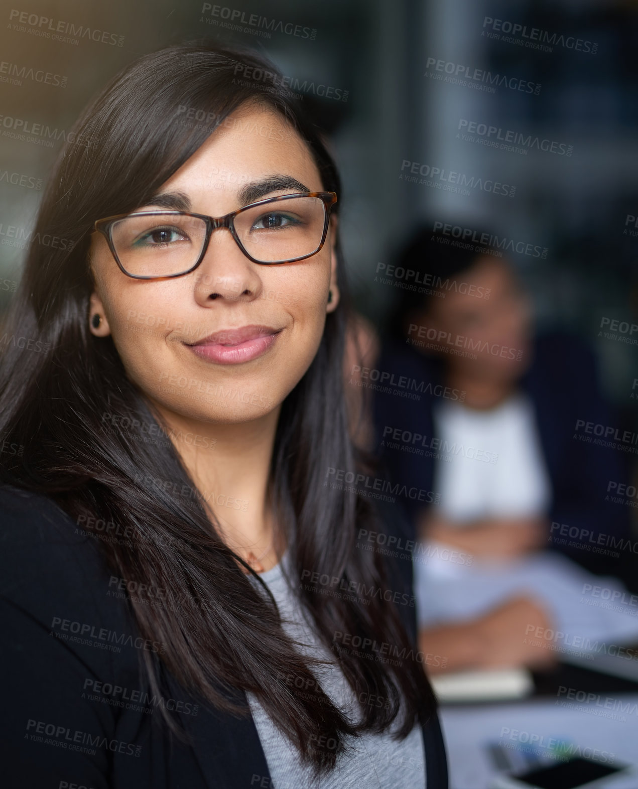 Buy stock photo Portrait of a smiling young businesswoman in an office with colleagues in the background