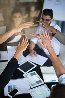 Buy stock photo Shot of a group of coworkers with their hands in a huddle while sitting together around a table in an office