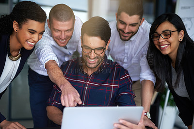 Buy stock photo Shot of a group of colleagues working together around a laptop in an office
