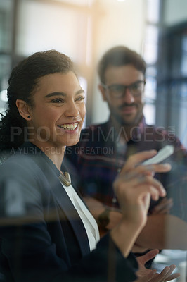 Buy stock photo Shot of two colleagues brainstorming together on a glass wall in an office