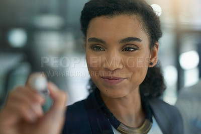 Buy stock photo Shot of a young businesswoman brainstorming on a glass wall in an office