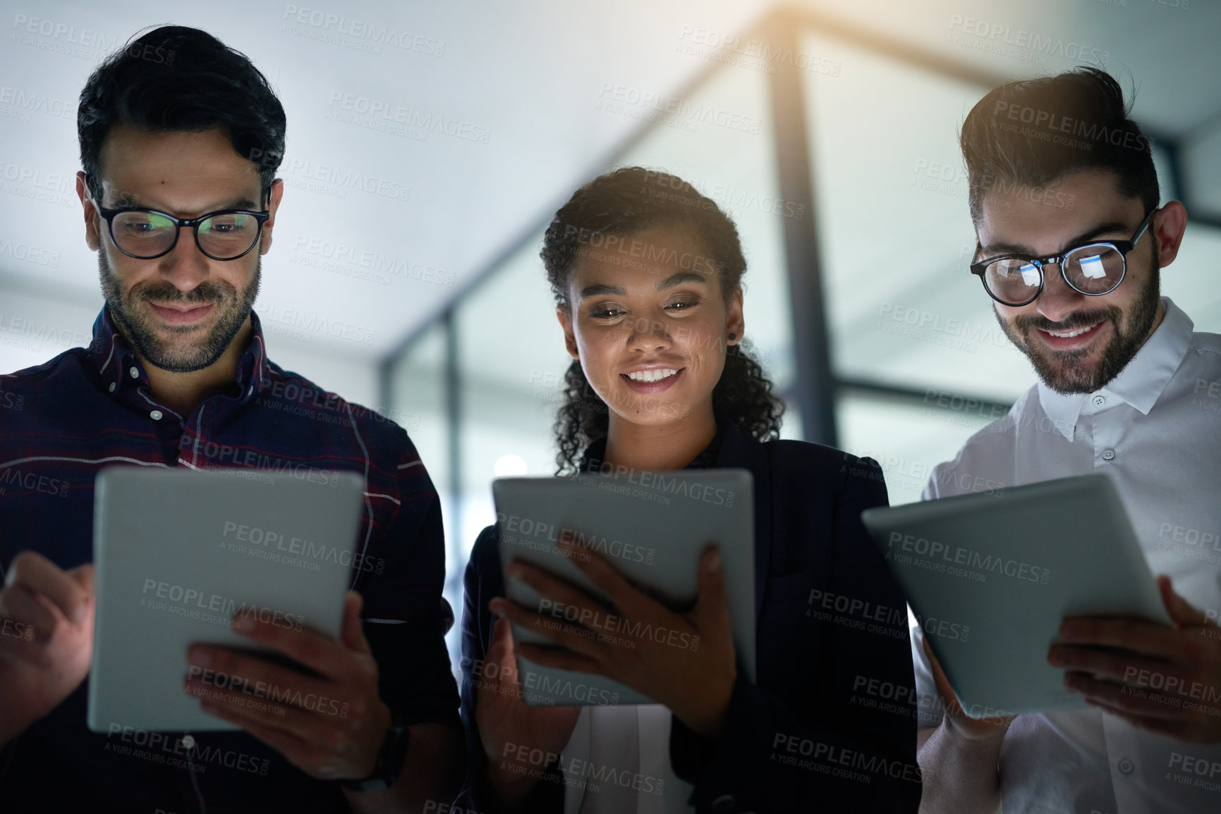 Buy stock photo Shot of three colleagues using digital tablets while standing together in an office