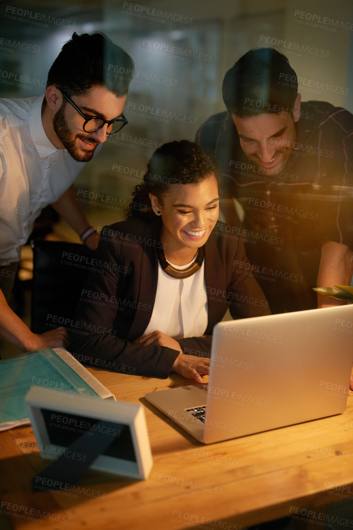 Buy stock photo Shot of a group of businesspeople using a laptop while working overtime in the office