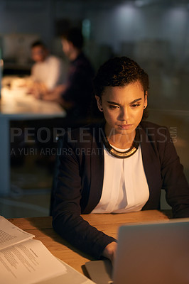 Buy stock photo Shot of a young businesswoman using her laptop while working overtime in the office