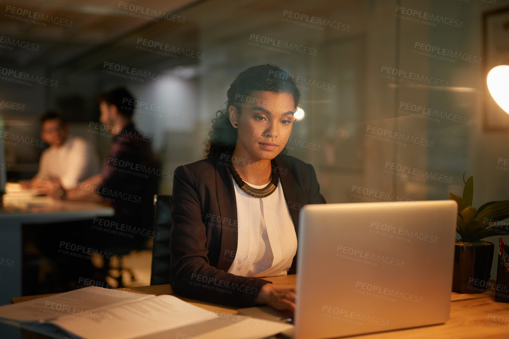 Buy stock photo Shot of a young businesswoman using her laptop while working overtime in the office