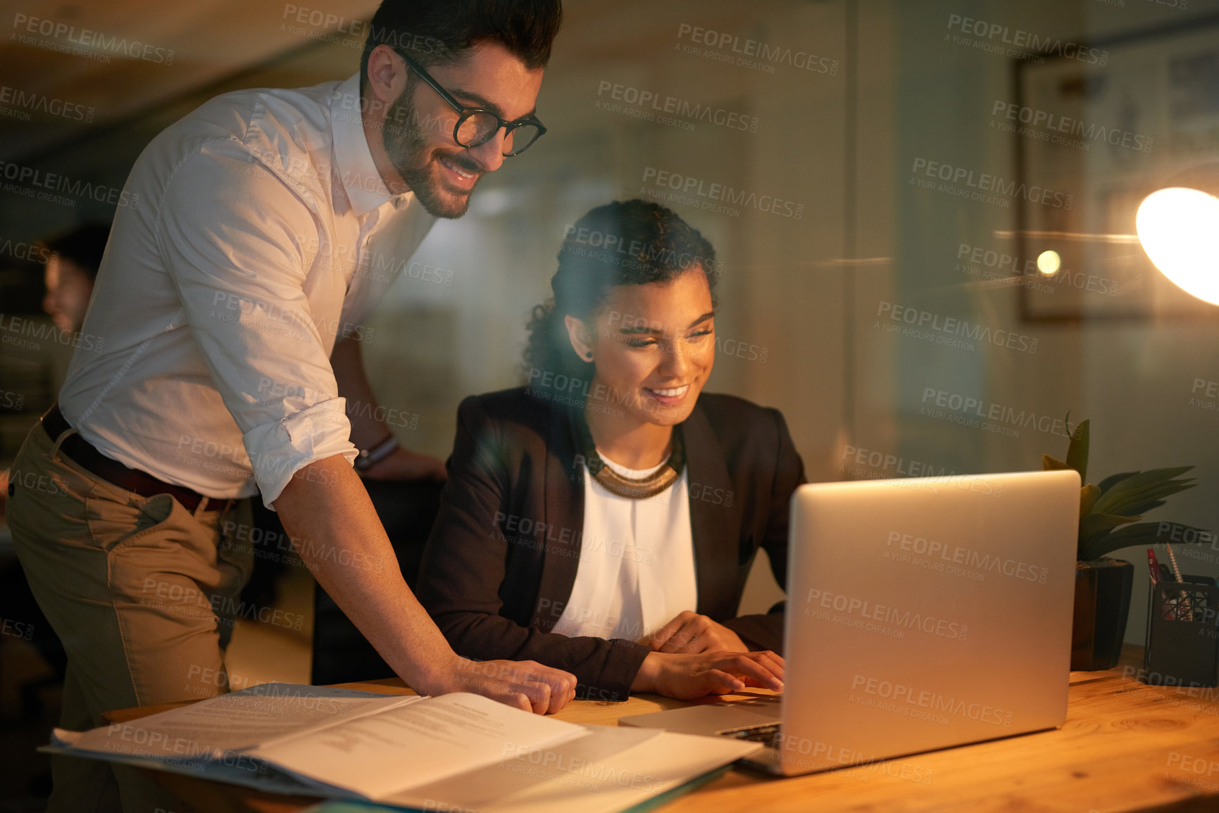 Buy stock photo Laptop, man and woman in night, document and overtime for project of web designer, creativity and smile. Startup, work and employees in collaboration, happy and online together or teamwork in office